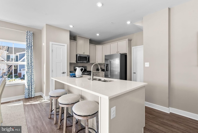 kitchen featuring sink, dark hardwood / wood-style floors, a kitchen breakfast bar, an island with sink, and stainless steel appliances