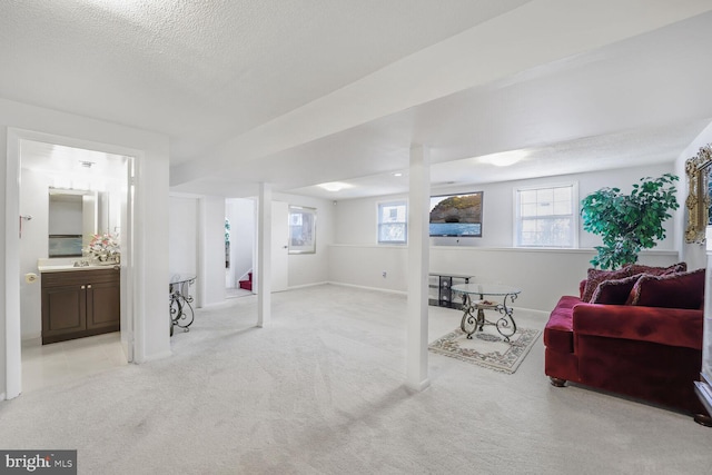 below grade area with baseboards, a textured ceiling, and light colored carpet