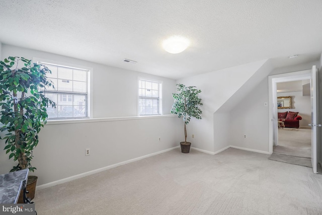 interior space with light carpet, a textured ceiling, and visible vents