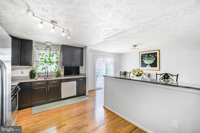 kitchen with stainless steel appliances, light wood-style floors, a sink, and a textured ceiling