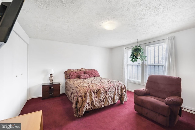 bedroom with visible vents, dark carpet, a textured ceiling, and baseboards