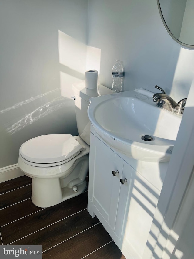 bathroom with toilet, vanity, and hardwood / wood-style flooring