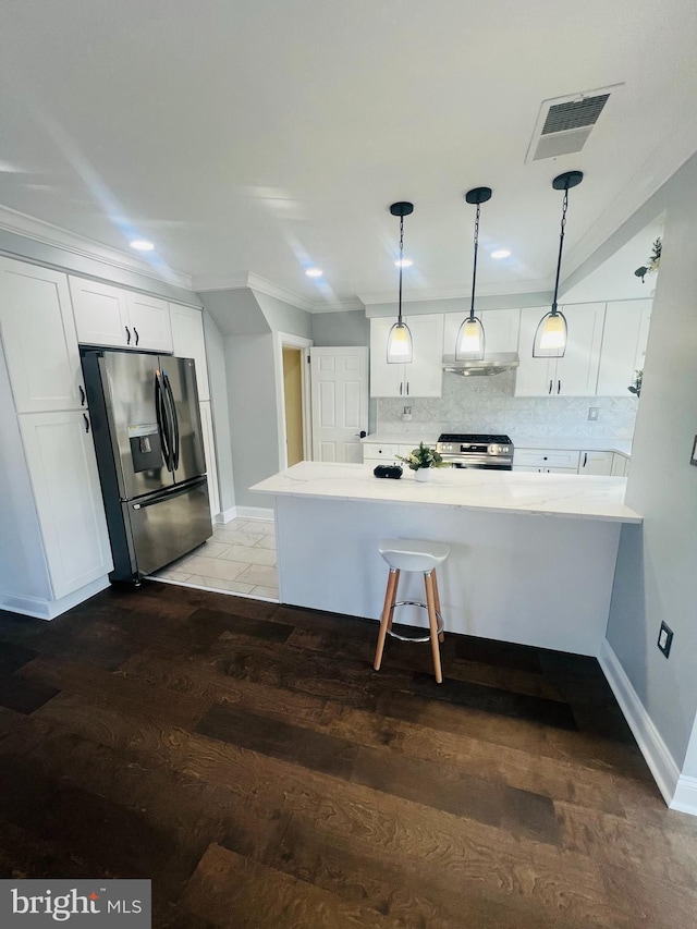 kitchen featuring white cabinetry, tasteful backsplash, hanging light fixtures, dark hardwood / wood-style floors, and appliances with stainless steel finishes