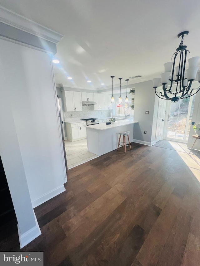 kitchen with white cabinetry, a kitchen bar, wood-type flooring, a kitchen island, and a notable chandelier