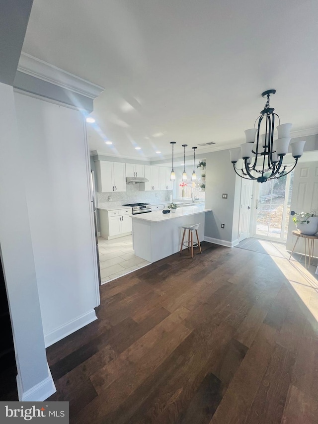 kitchen featuring decorative light fixtures, white cabinets, a kitchen island, crown molding, and dark wood-type flooring