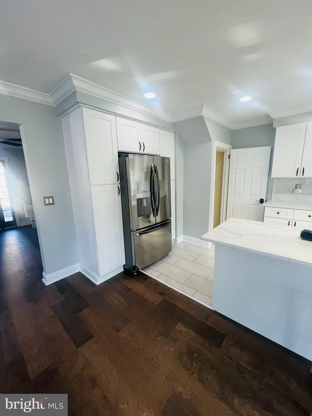 kitchen featuring white cabinets, ornamental molding, stainless steel fridge with ice dispenser, light stone countertops, and dark wood-type flooring