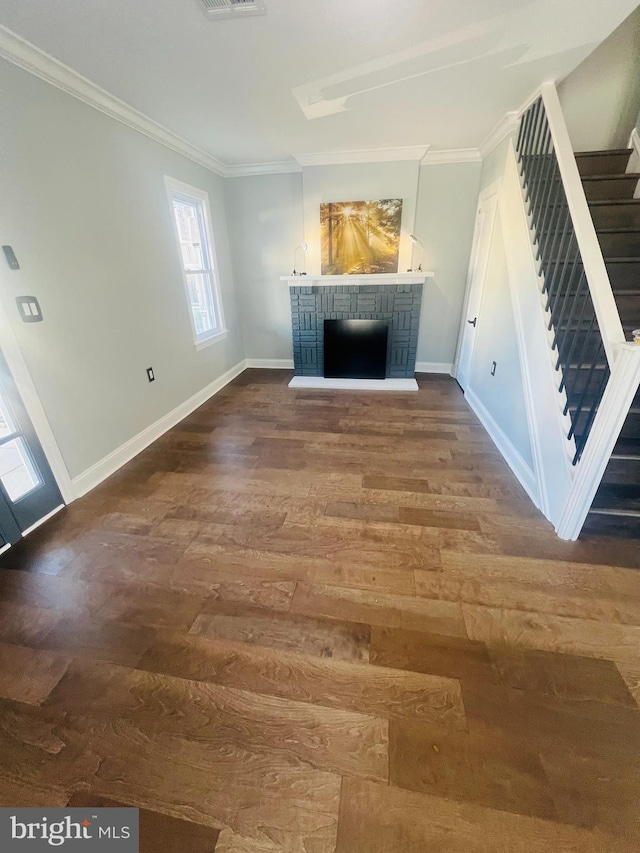 unfurnished living room featuring wood-type flooring, a brick fireplace, and crown molding