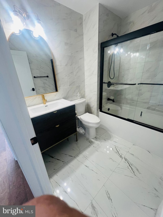 full bathroom featuring toilet, shower / bath combination with glass door, tile walls, and vanity