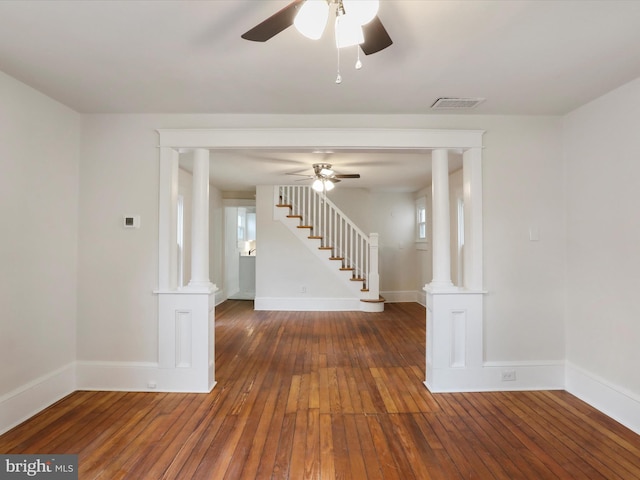 empty room featuring ceiling fan, dark hardwood / wood-style floors, and decorative columns