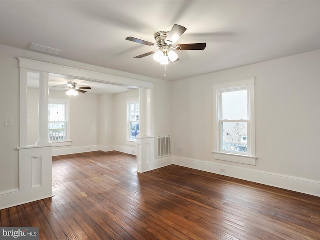 spare room featuring decorative columns, ceiling fan, and dark hardwood / wood-style flooring