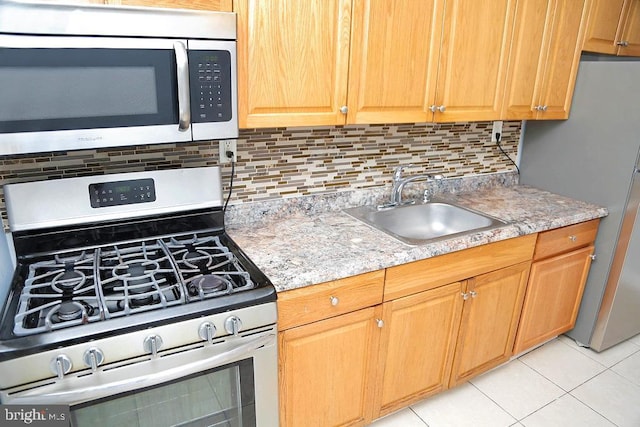 kitchen with light stone countertops, light tile patterned floors, tasteful backsplash, appliances with stainless steel finishes, and sink