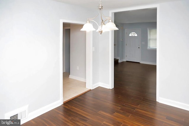 unfurnished dining area featuring an inviting chandelier and dark hardwood / wood-style floors