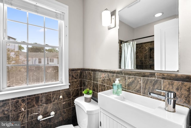 bathroom with tile walls, toilet, vanity, and a shower with curtain