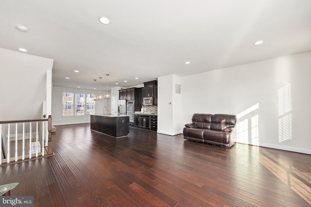 unfurnished living room with sink, dark wood-type flooring, and a notable chandelier