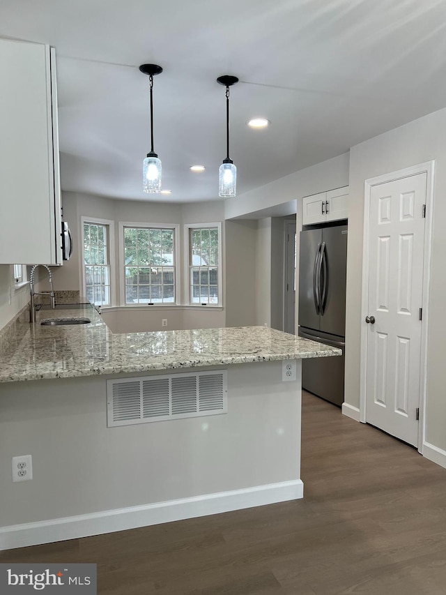 kitchen featuring stainless steel appliances, kitchen peninsula, pendant lighting, white cabinets, and sink