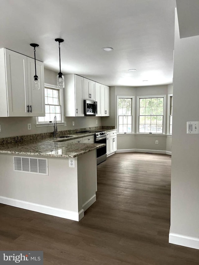 kitchen featuring stone counters, kitchen peninsula, pendant lighting, sink, and white cabinetry