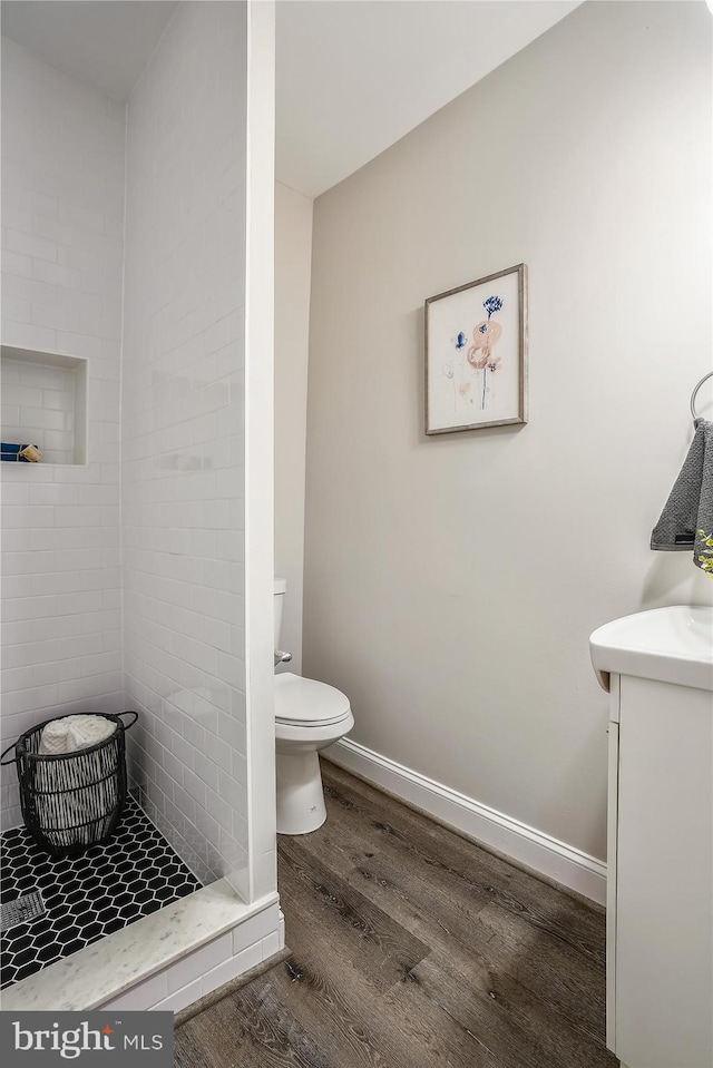 bathroom featuring toilet, vanity, walk in shower, and hardwood / wood-style floors