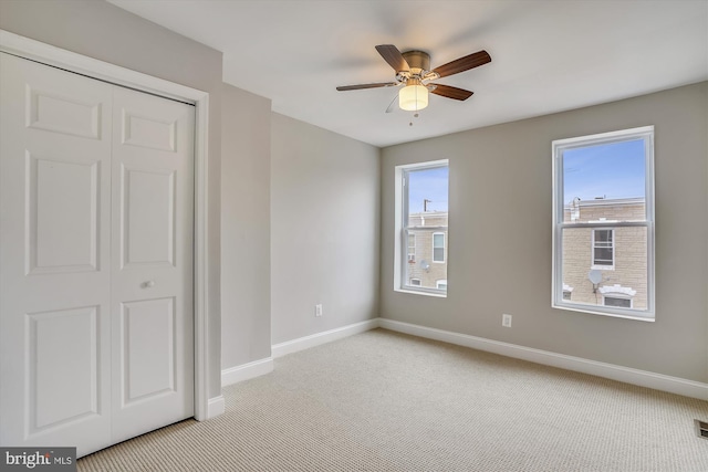 unfurnished bedroom with ceiling fan, a closet, and light carpet