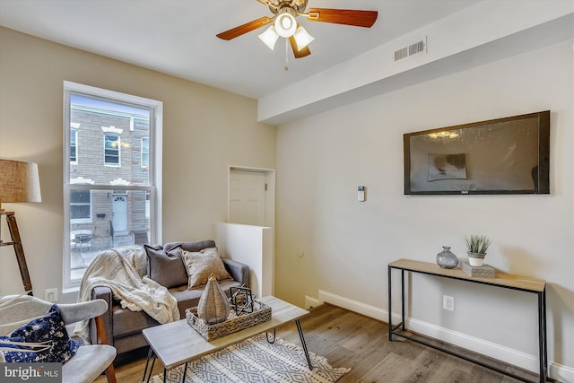 sitting room with ceiling fan and wood-type flooring