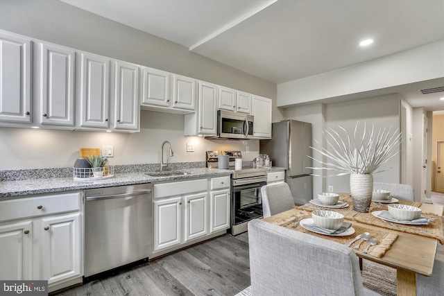 kitchen with light hardwood / wood-style flooring, stainless steel appliances, white cabinets, and sink