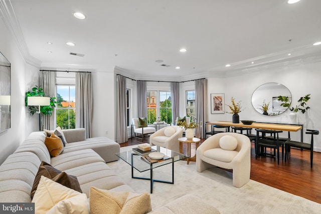 living room featuring light wood-type flooring, a wealth of natural light, and crown molding