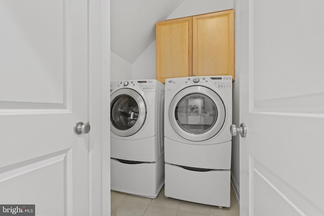 laundry area featuring cabinets, light tile patterned floors, and washer and clothes dryer