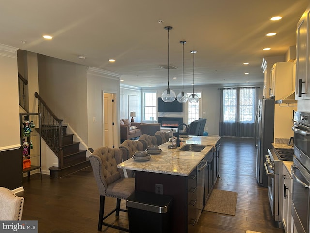 kitchen with a center island with sink, a breakfast bar area, stainless steel appliances, light stone countertops, and sink