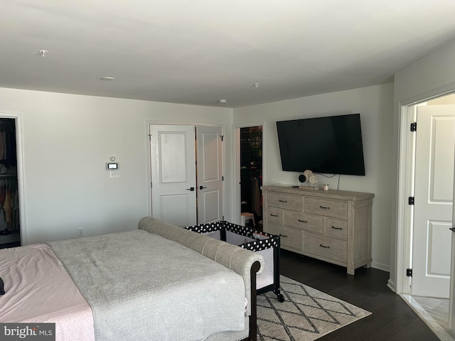 bedroom with a closet, a walk in closet, and dark hardwood / wood-style floors