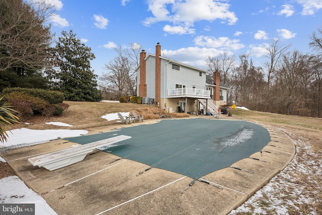 view of swimming pool featuring central AC unit, a diving board, and a patio