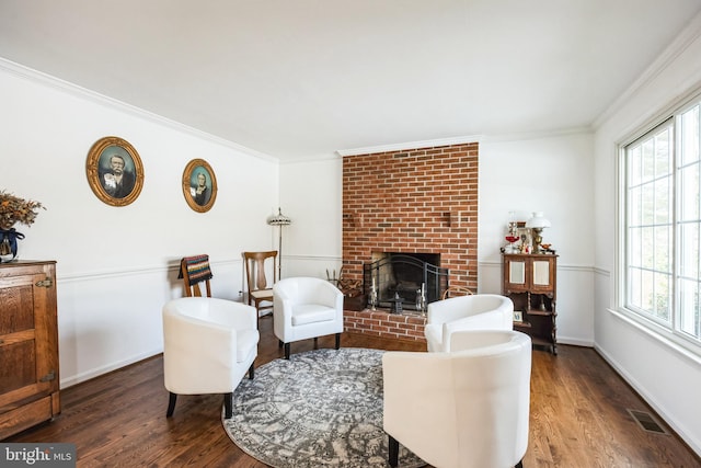 living room with dark hardwood / wood-style flooring, a healthy amount of sunlight, ornamental molding, and a fireplace