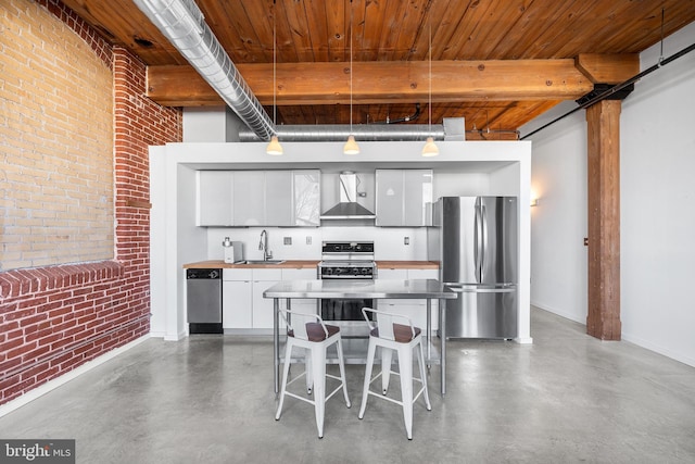 kitchen featuring stainless steel appliances, sink, white cabinetry, brick wall, and pendant lighting