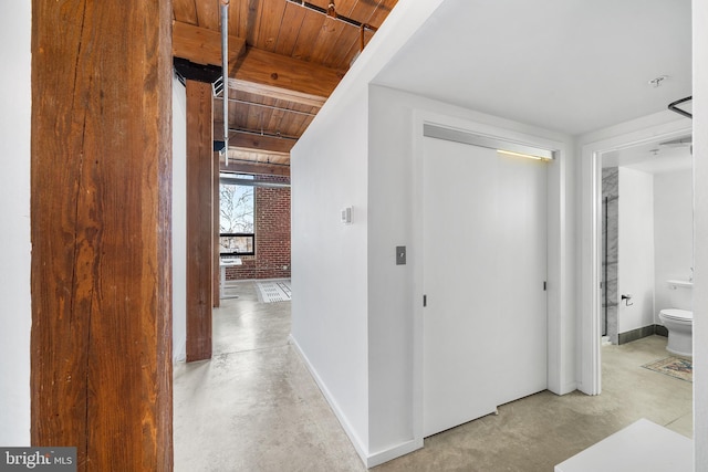 hallway featuring wood ceiling and brick wall