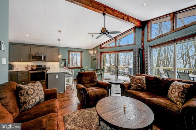 living room with beam ceiling, dark wood-type flooring, ceiling fan with notable chandelier, and high vaulted ceiling