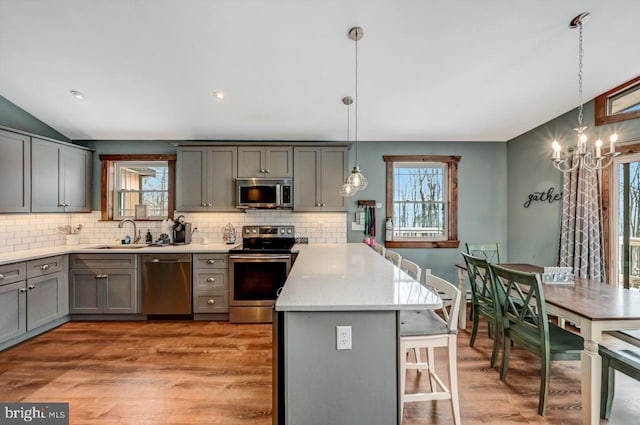 kitchen with pendant lighting, sink, light wood-type flooring, plenty of natural light, and stainless steel appliances