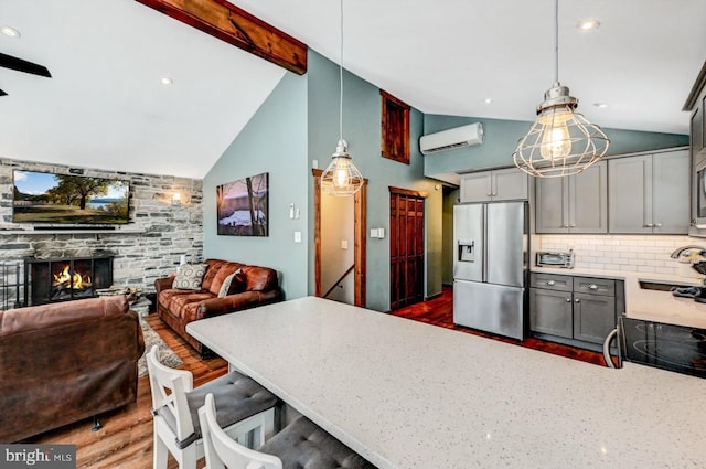 kitchen featuring decorative light fixtures, tasteful backsplash, stainless steel fridge, a wall mounted AC, and gray cabinetry