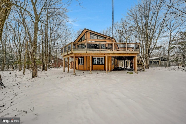 snow covered back of property featuring a wooden deck