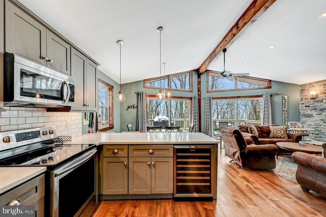 kitchen featuring beverage cooler, appliances with stainless steel finishes, kitchen peninsula, and hanging light fixtures