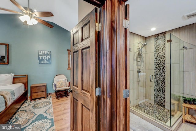 bathroom featuring ceiling fan, hardwood / wood-style floors, a shower with shower door, and lofted ceiling