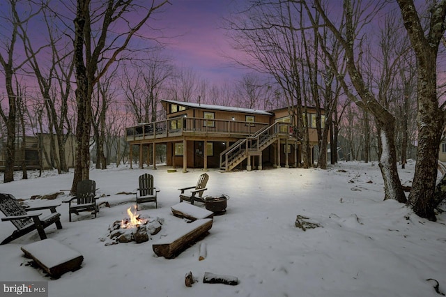 snow covered house with a wooden deck and a fire pit