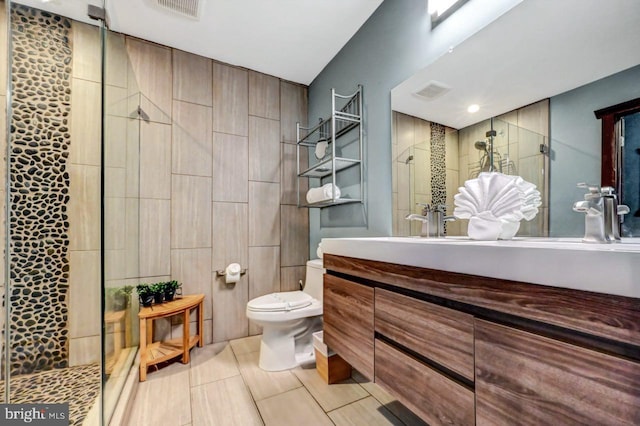 bathroom with toilet, tiled shower, and vanity