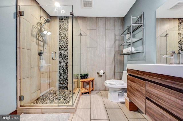 bathroom with a shower with shower door, vanity, and toilet