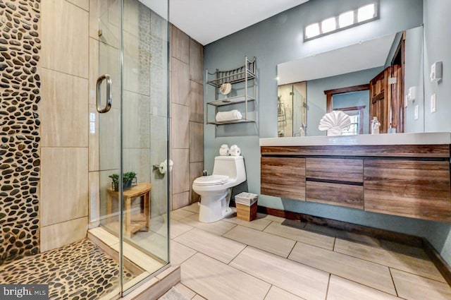 bathroom with toilet, vanity, and a shower with shower door