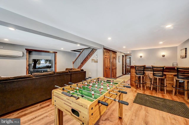 game room featuring hardwood / wood-style floors, bar, and a wall mounted air conditioner