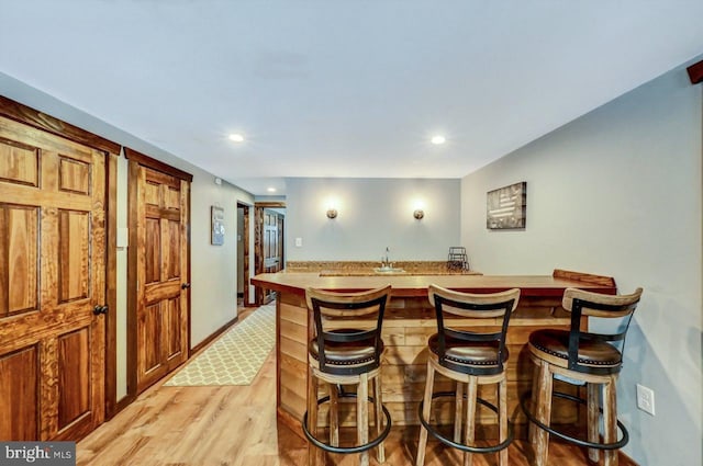 kitchen featuring a center island with sink, a kitchen bar, and light hardwood / wood-style flooring