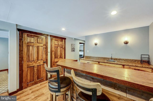 kitchen with wooden counters, sink, washer / dryer, and light hardwood / wood-style flooring