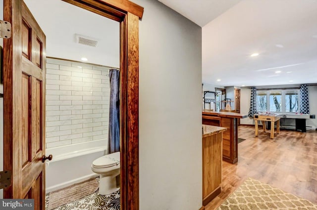 bathroom with toilet, baseboard heating, hardwood / wood-style flooring, and shower / tub combo with curtain