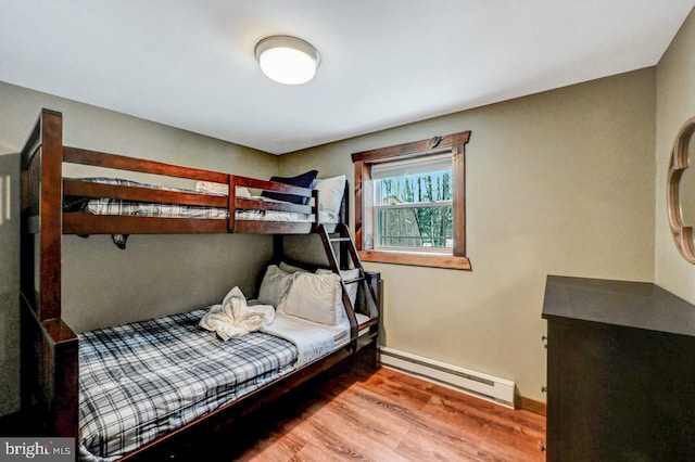 bedroom featuring hardwood / wood-style floors and a baseboard heating unit