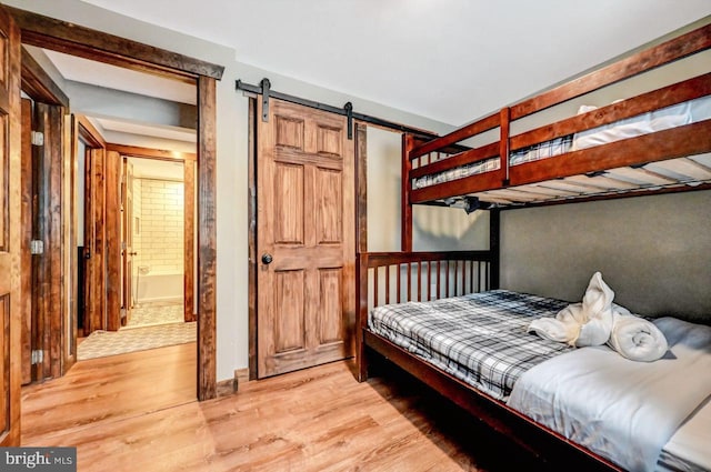 bedroom featuring light hardwood / wood-style floors, connected bathroom, and a barn door