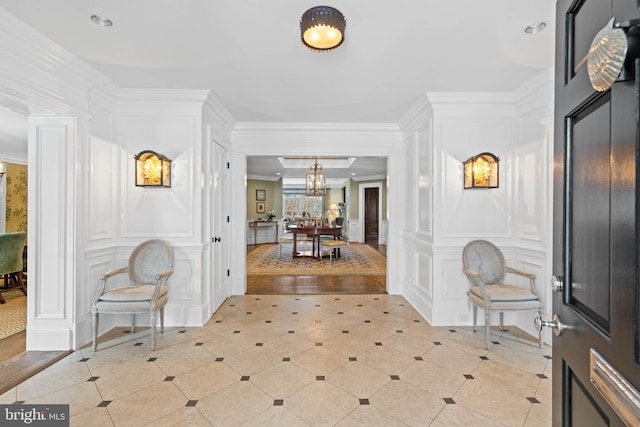 entrance foyer with an inviting chandelier, crown molding, and light tile patterned flooring