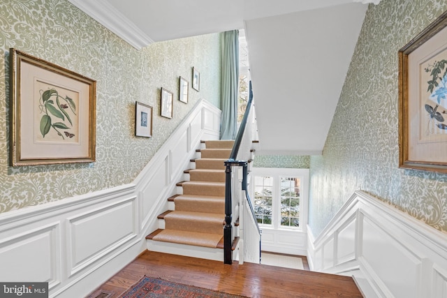 stairs with ornamental molding and hardwood / wood-style floors